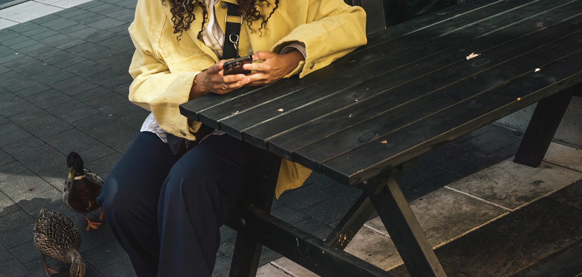 Kvinna sitter på en bänk och kollar i sin telefon
