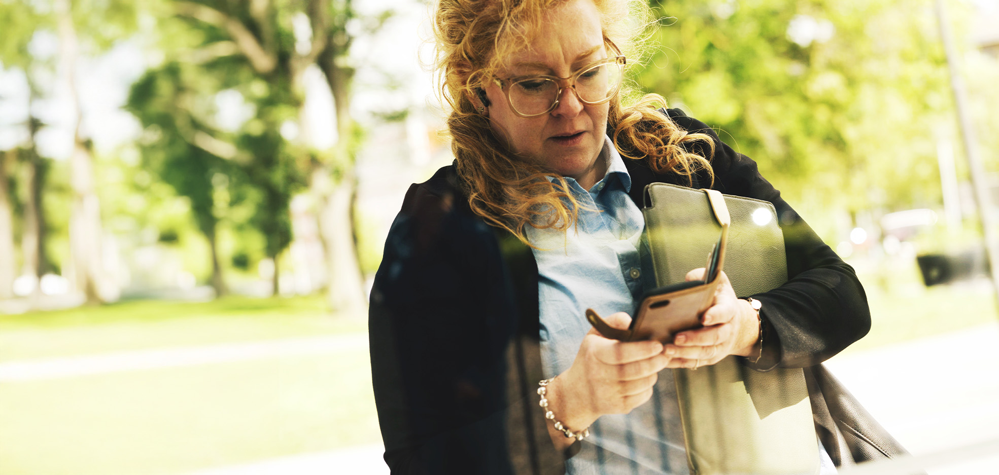 Kvinna står utomhus och kollar i sin telefon