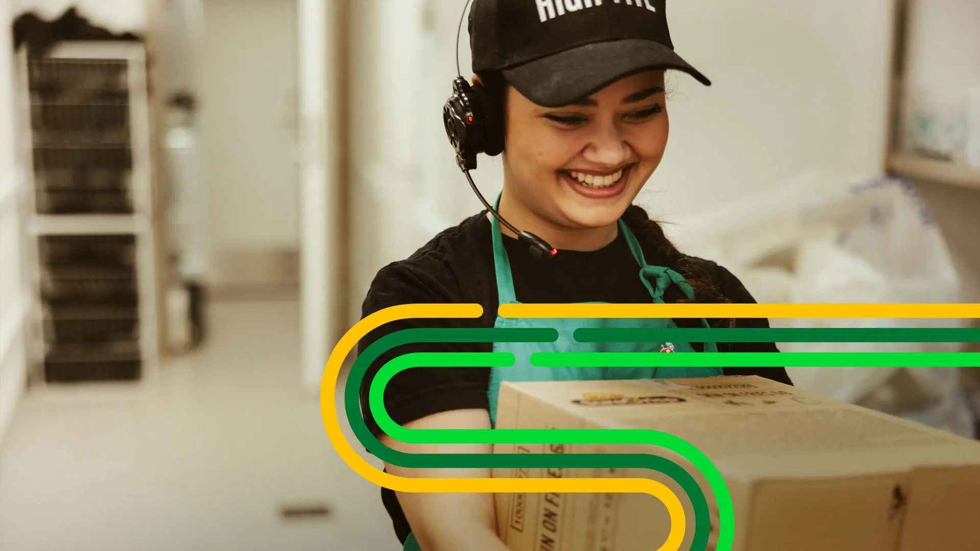 Smiling worker wearing a headset and cap, holding a package. Bright swirled lines overlay. Background shows a blurred indoor setting.