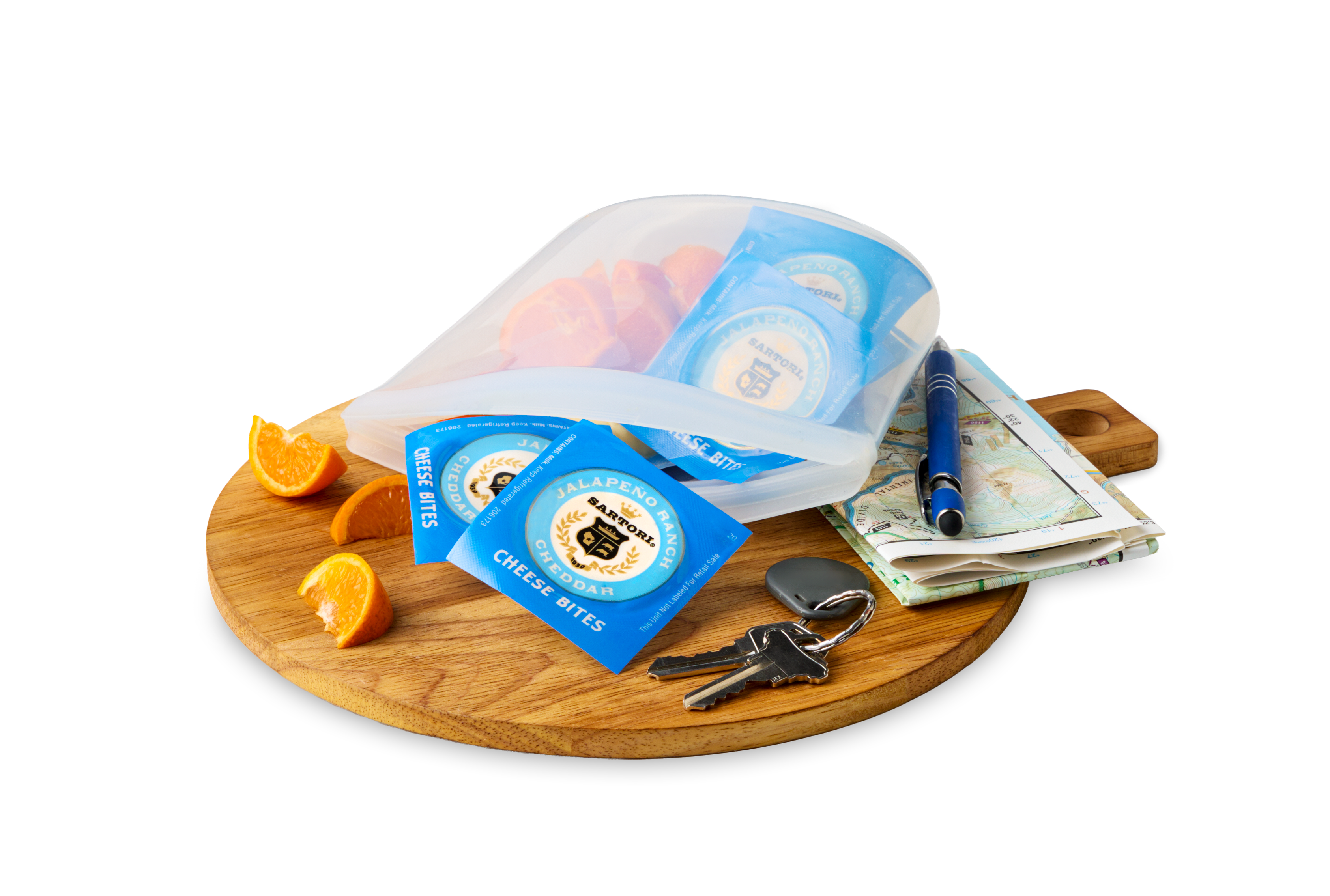 Cheese bites in a silicone bag with cut oranges, keys, a pen, and maps on a wooden board.