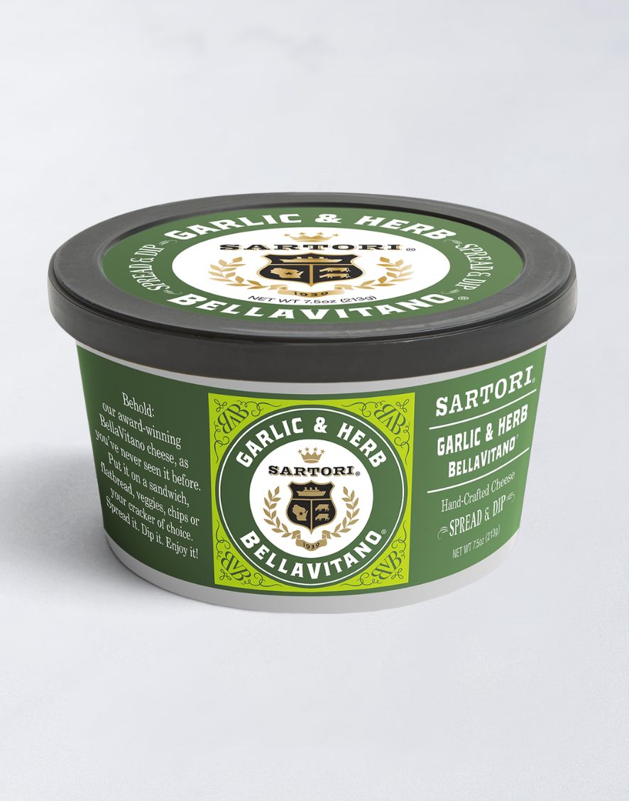 A tub of Sartori Garlic & Herb Bellavitano cheese spread, featuring a green label with the brand's logo and decorative design.