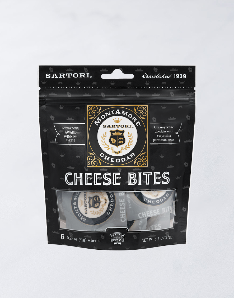 Black package of Sartori MontAmore Cheddar Cheese Bites, displaying the logo and cheese wheels through a transparent section.