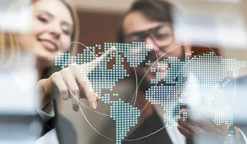 Picture shows two people in front of a world map
