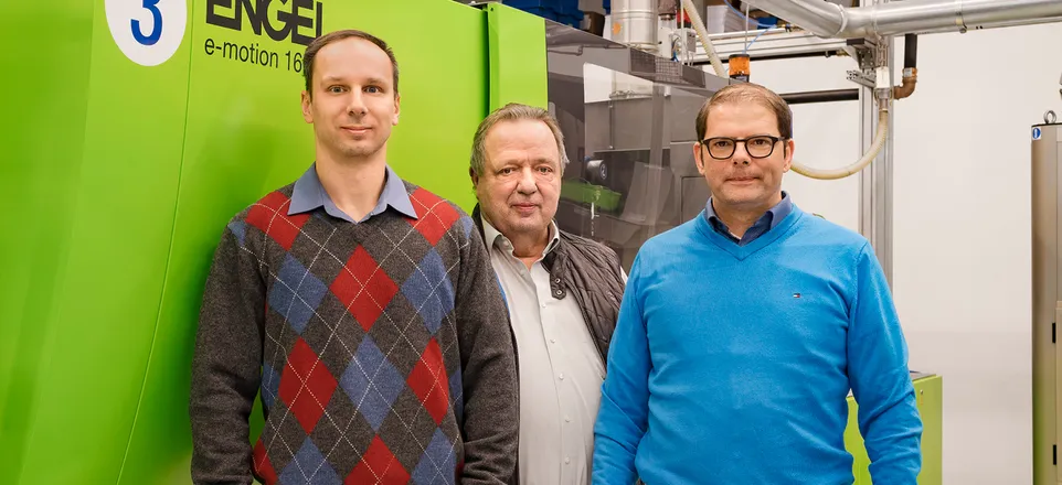 Image shows Konstantin Rezdelenko, Norbert Kuhl, and Martin Wassmer from Bio-Caps standing in front of an ENGEL e-motion injection molding machine.