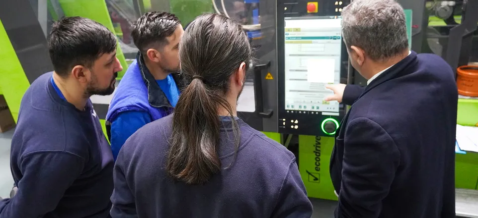 Image shows people in front of an injection moulding machine demonstrating iQ weight control