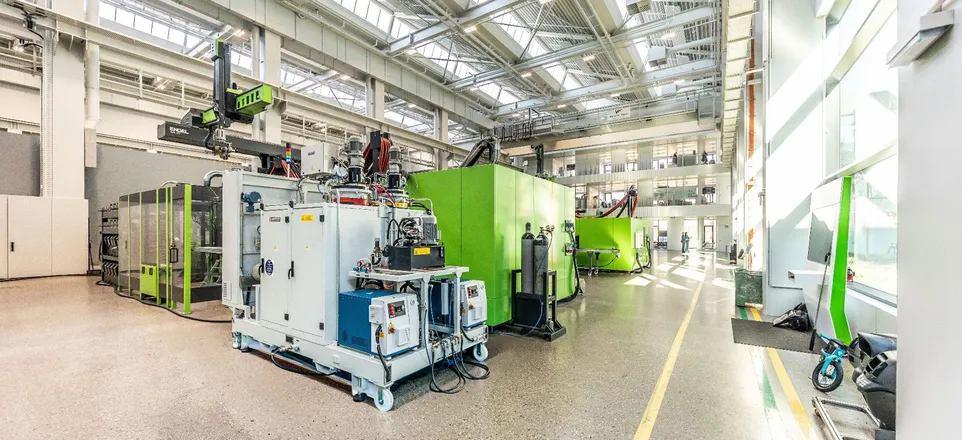 Image shows a green injection moulding machine with a light grey PUR dosing system for clearmelt in the foreground.