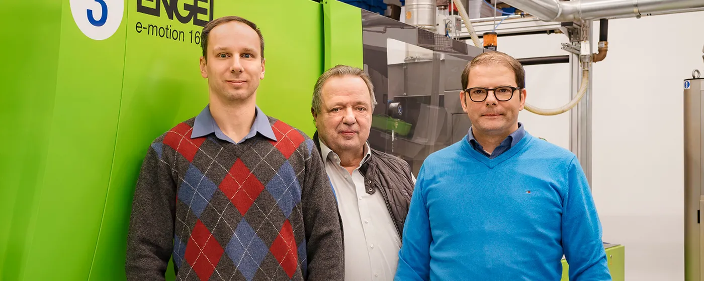 Image shows Konstantin Rezdelenko, Norbert Kuhl, and Martin Wassmer from Bio-Caps standing in front of an ENGEL e-motion injection molding machine.