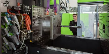 Picture shows production employee in front of an open mould room of an ENGEL injection moulding machine
