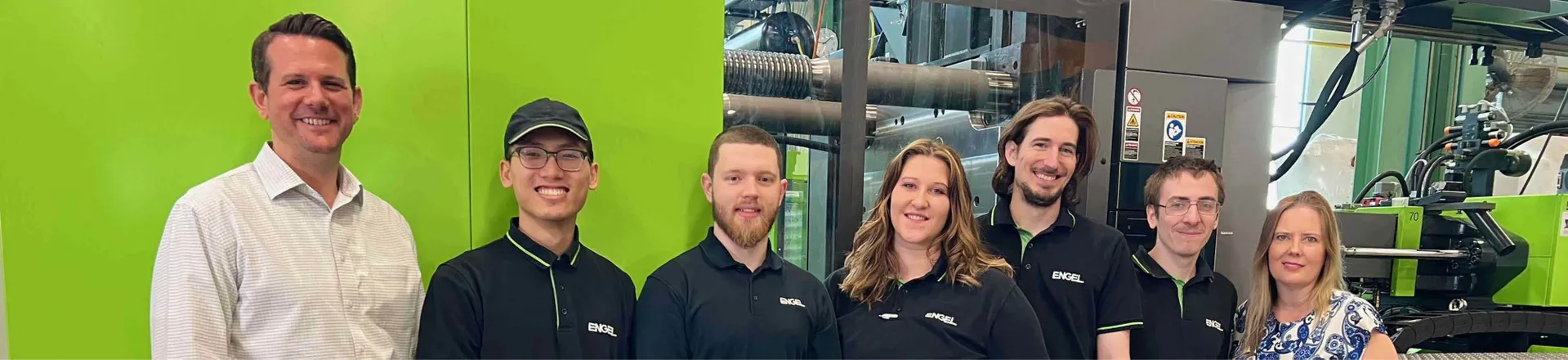 Image shows apprentices from ENGEL in front of an injection molding machine