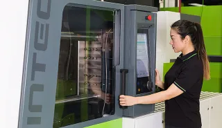 Bild zeigt Maschinenbedienerin an der C3 Steuerung der WINTEC Spritzgießmaschine