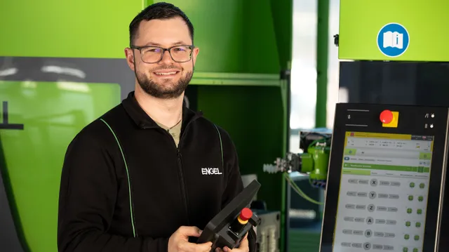 Bild zeigt Mann vor einer Spritzgießmaschinen-Steuerung und einem Handgerät