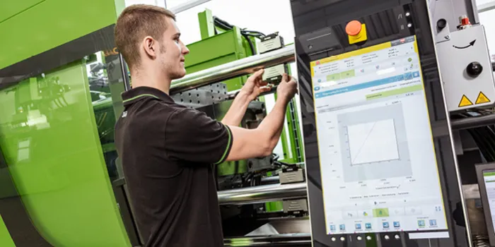 Picture shows ENGEL service technicians performing preventive maintenance work on an injection moulding machine.