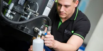 Picture shows oil maintenance on an injection moulding machine by an ENGEL service technician.