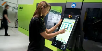 Picture shows machine operator in front of a green injection moulding machine from ENGEL
