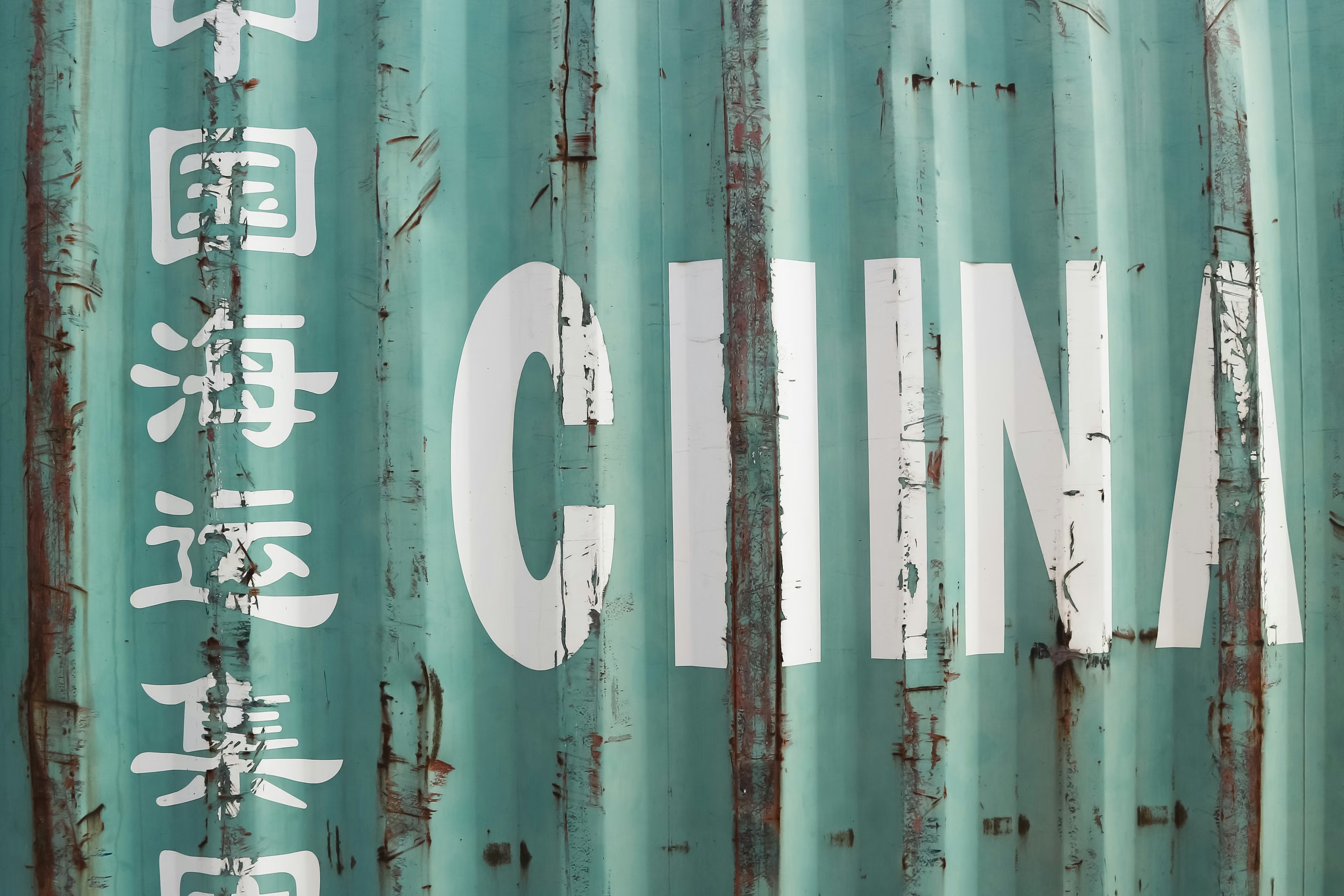 Rusty green shipping container with large white letters "CHINA" and Chinese characters on the side.
