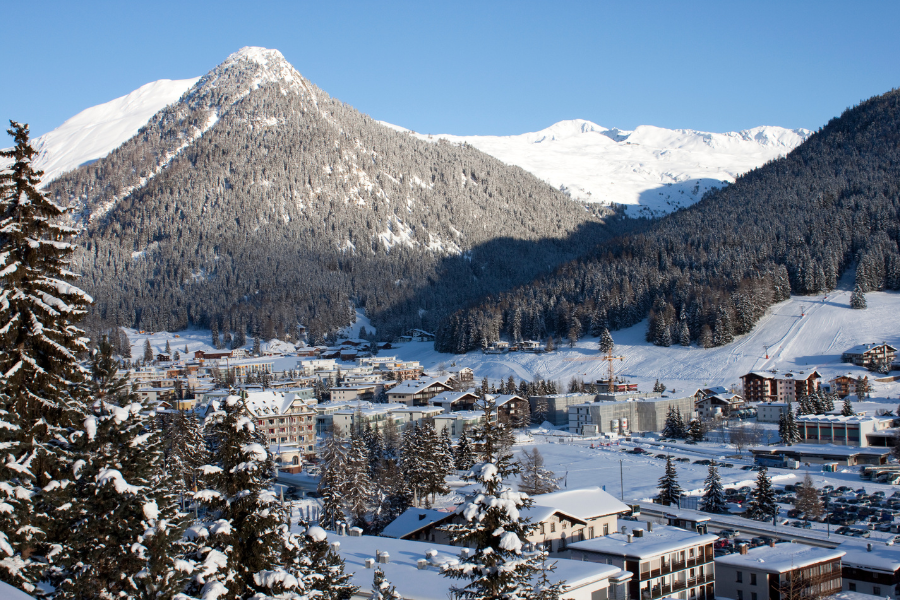 Landscape shot of a snowy village with the Alps in the background