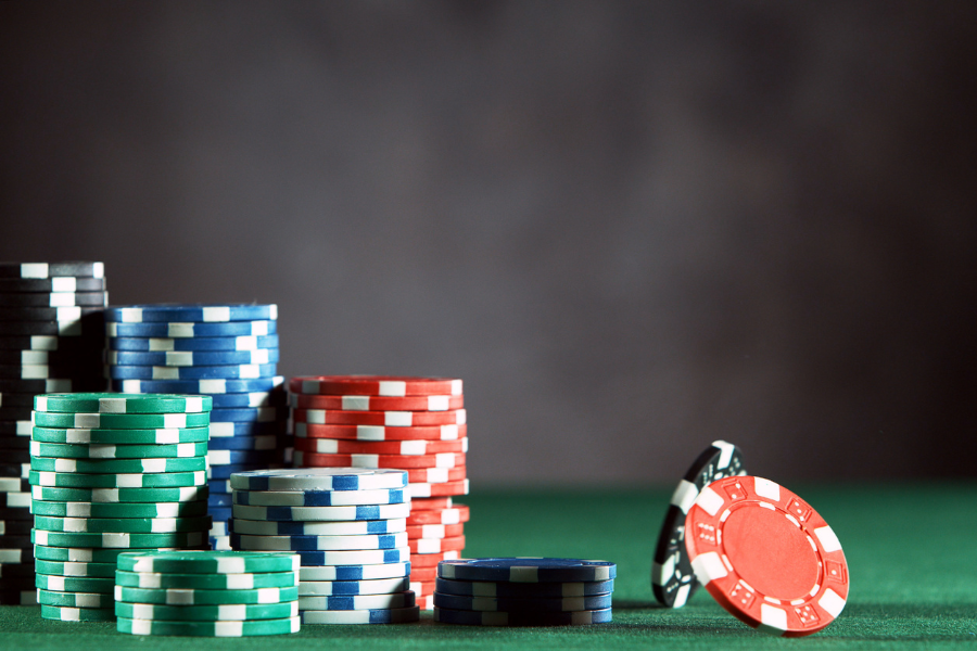 Stacks of green, blue, red, and black poker chips on a green felt table, with a few chips leaning against each other on the right.