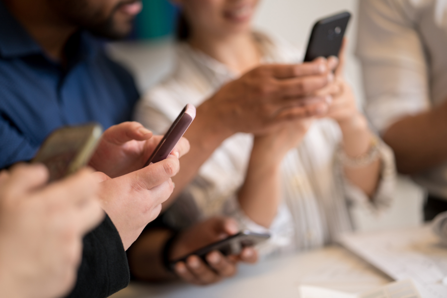 People holding and using smartphones, focusing on hands and devices in a social or business setting.