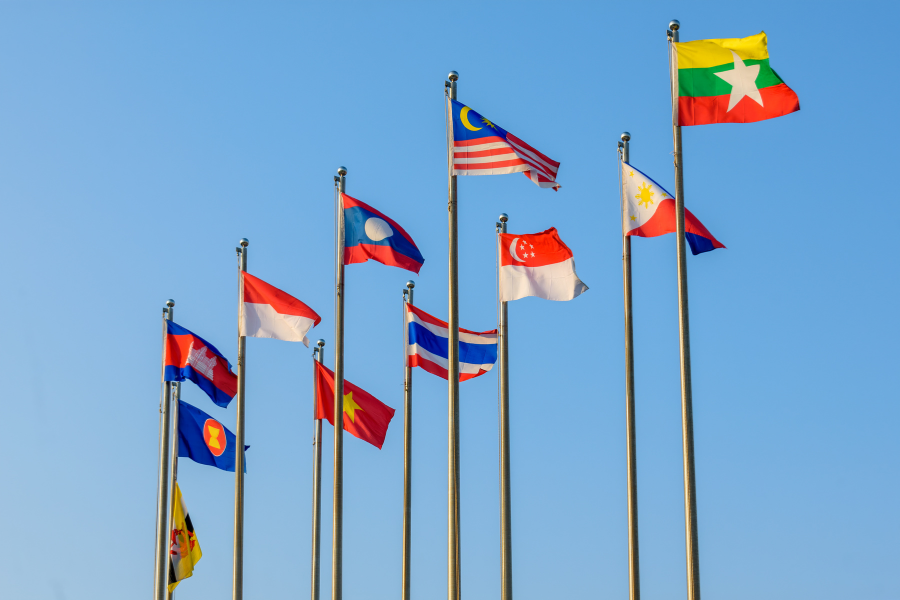 Ten ASEAN member flags on poles against a clear blue sky