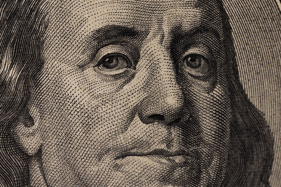 An extreme close-up of the Benjamin Franklin portrait on a $100 bill