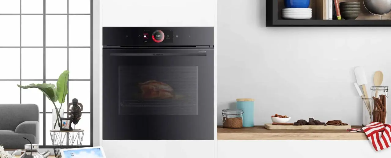 Zwarte Bosch oven in een wit met houten keuken. Rustige omgeving, groene plant.