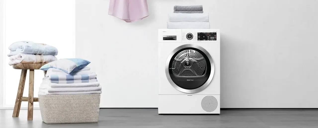 Bosch dryer with clean laundry in laundry basket next to it.