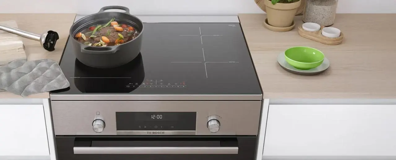 Een pan met groenten en vlees staat op een inductiefornuis.