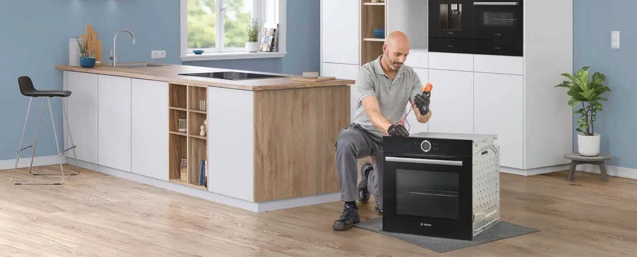Bosch technician checking a Bosch built-in oven in a kitchen.