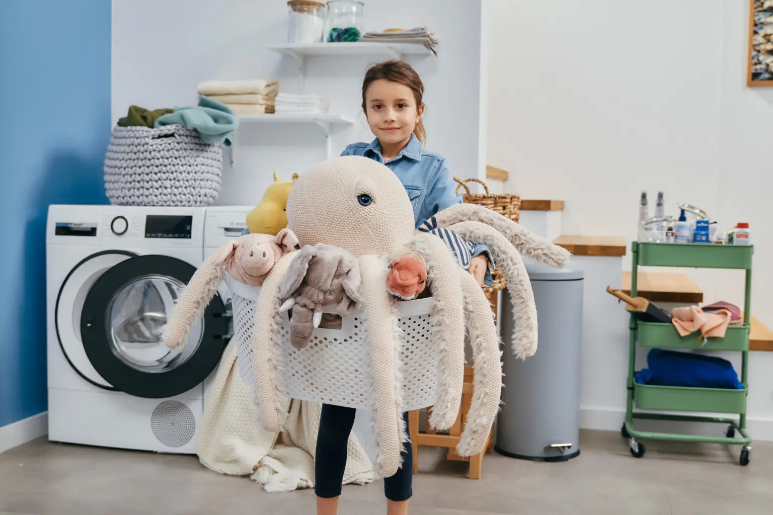 Een kind met een wasmand vol knuffel dieren.