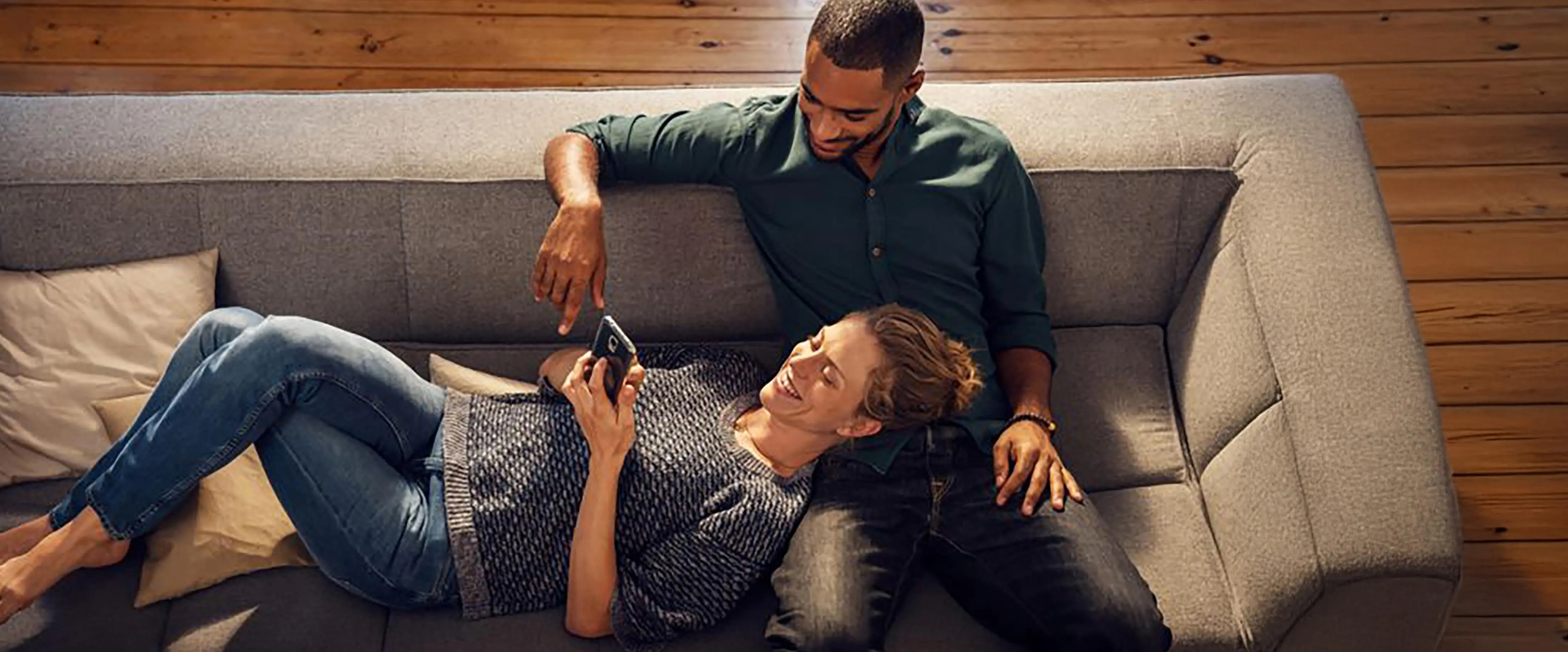 Woman and man relaxing on a spacious sofa in the living room.
