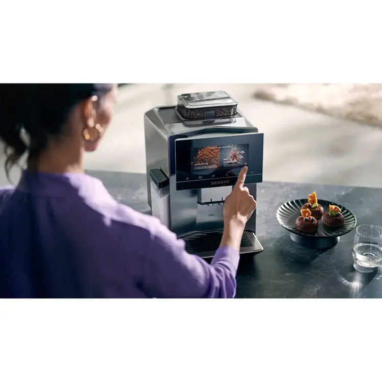 Frau beruehrt das Display eines Kaffeeautomaten.
