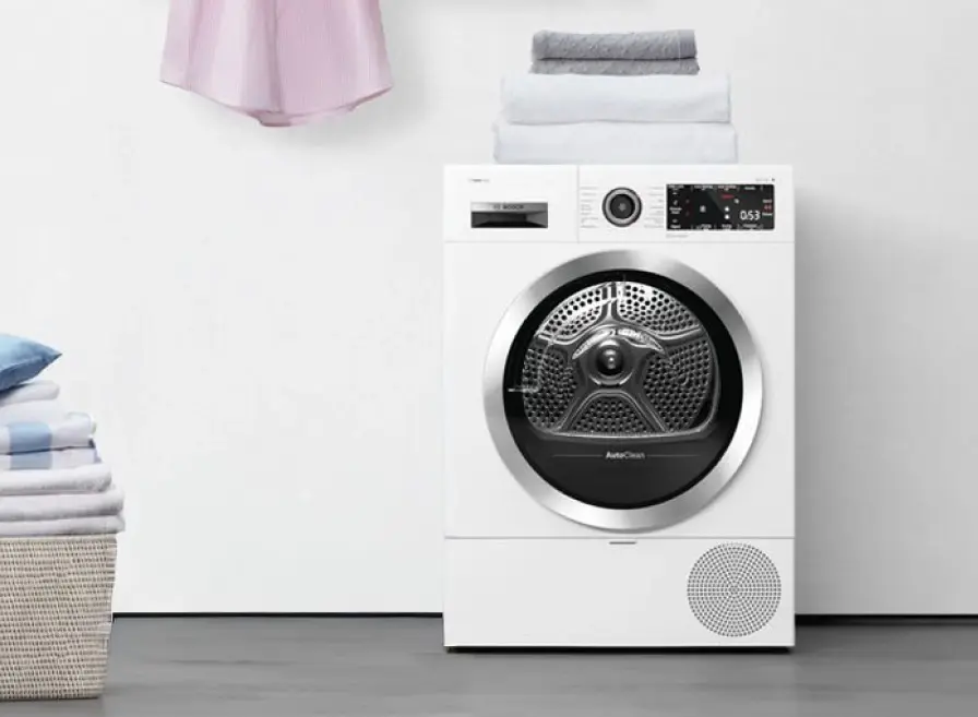 Bosch dryer with clean laundry in laundry basket next to it.