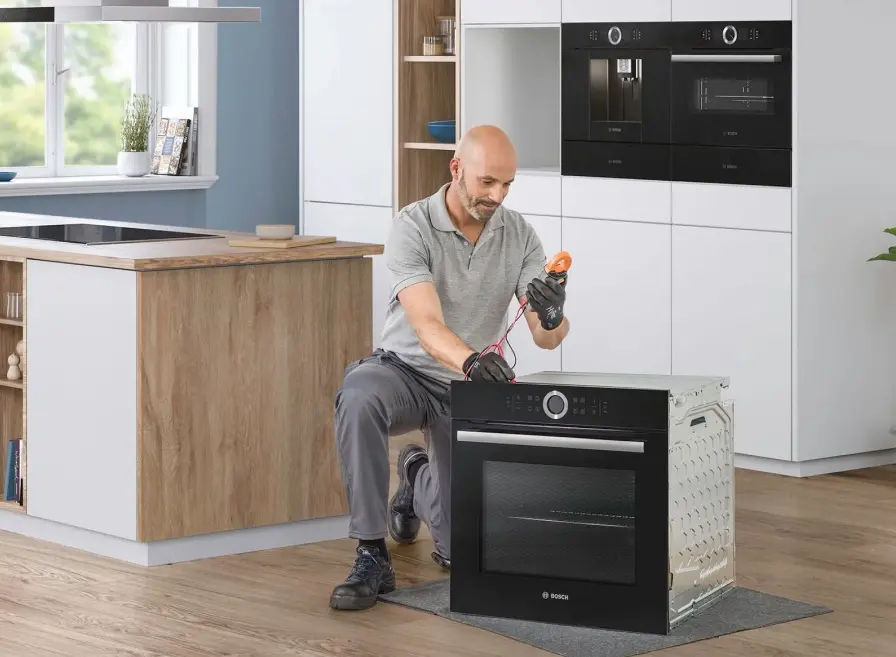 Bosch monteur kijkt een Bosch inbouwoven na in een keuken.