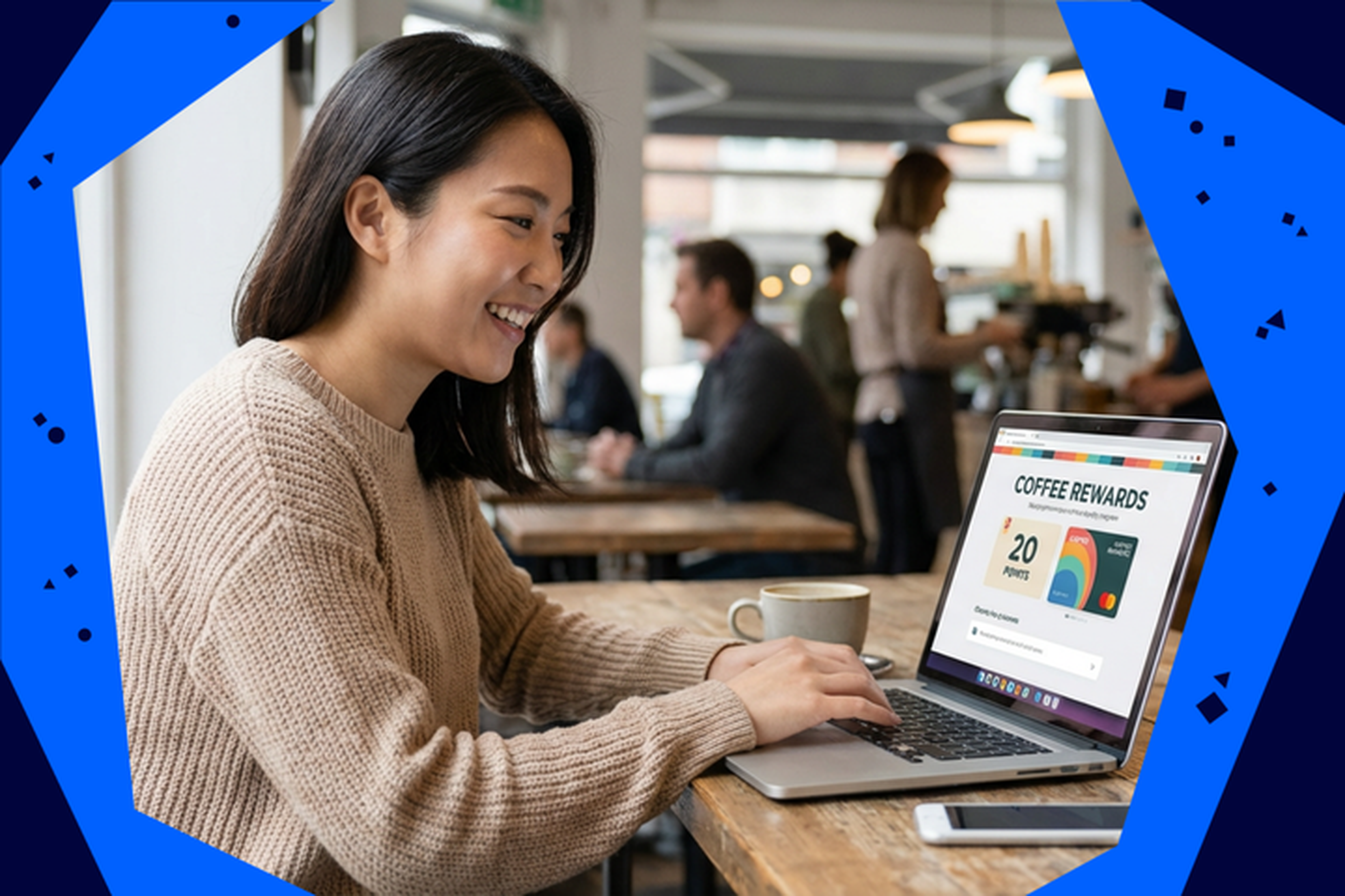 Smiling woman in a cafe using a laptop displaying a coffee rewards program, with a cup of coffee beside her; people in the background.