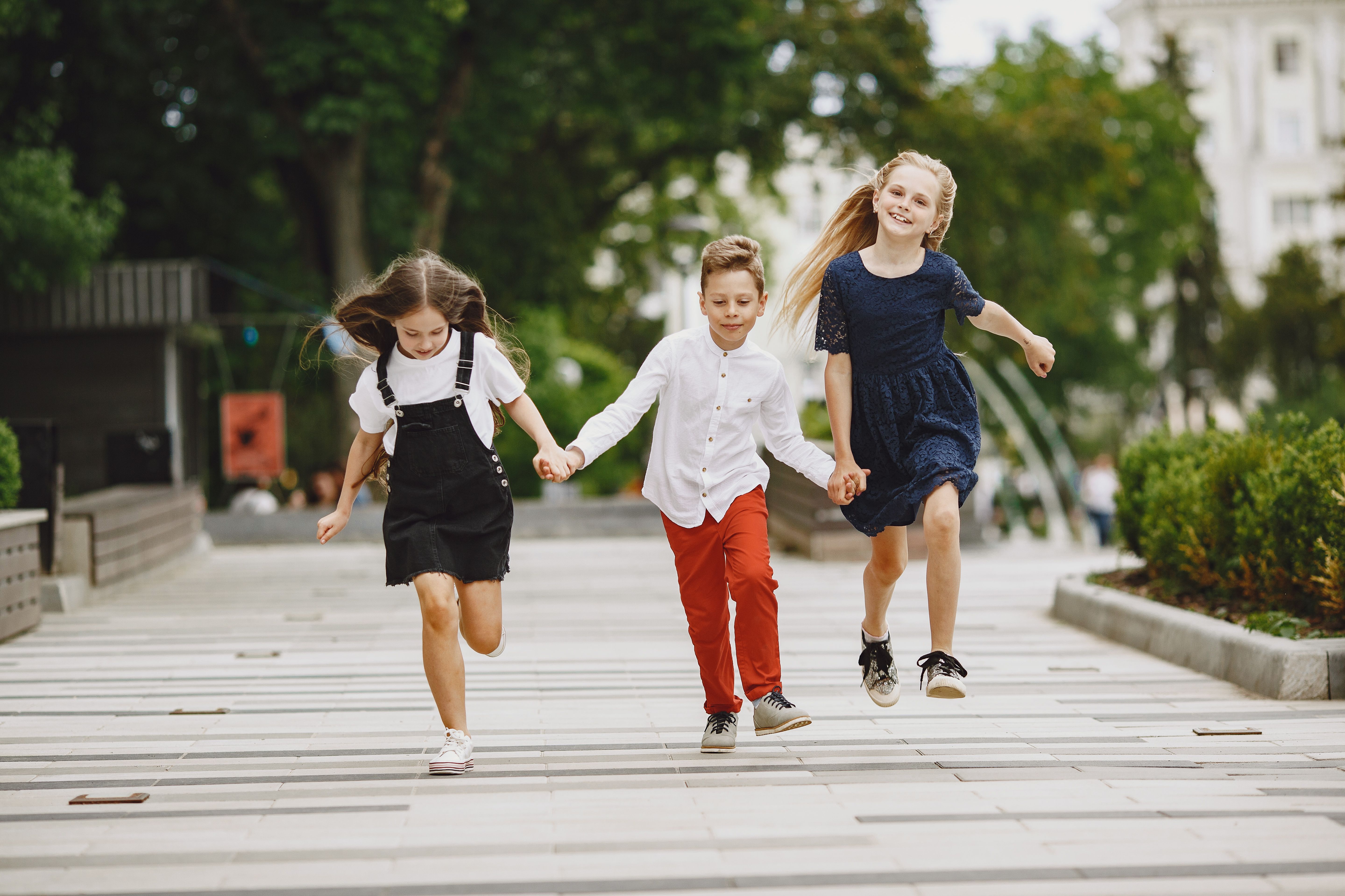 een jongen en twee meisjes rennen en huppelen op de openbare weg