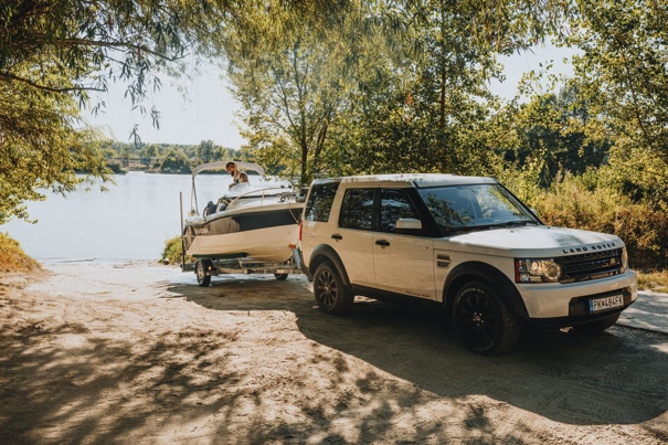 Boottrailer achter een witte land rover aan het water