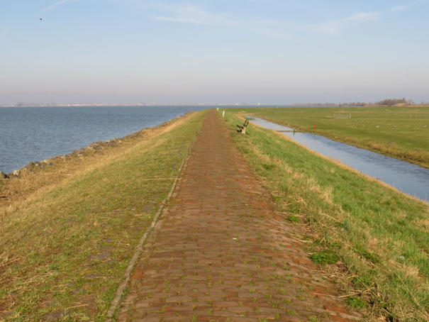 Goed onderhouden dijk met wandelpad en een bankje