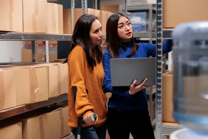 Warehouse staff using laptop to check orders and accounts in a storehouse