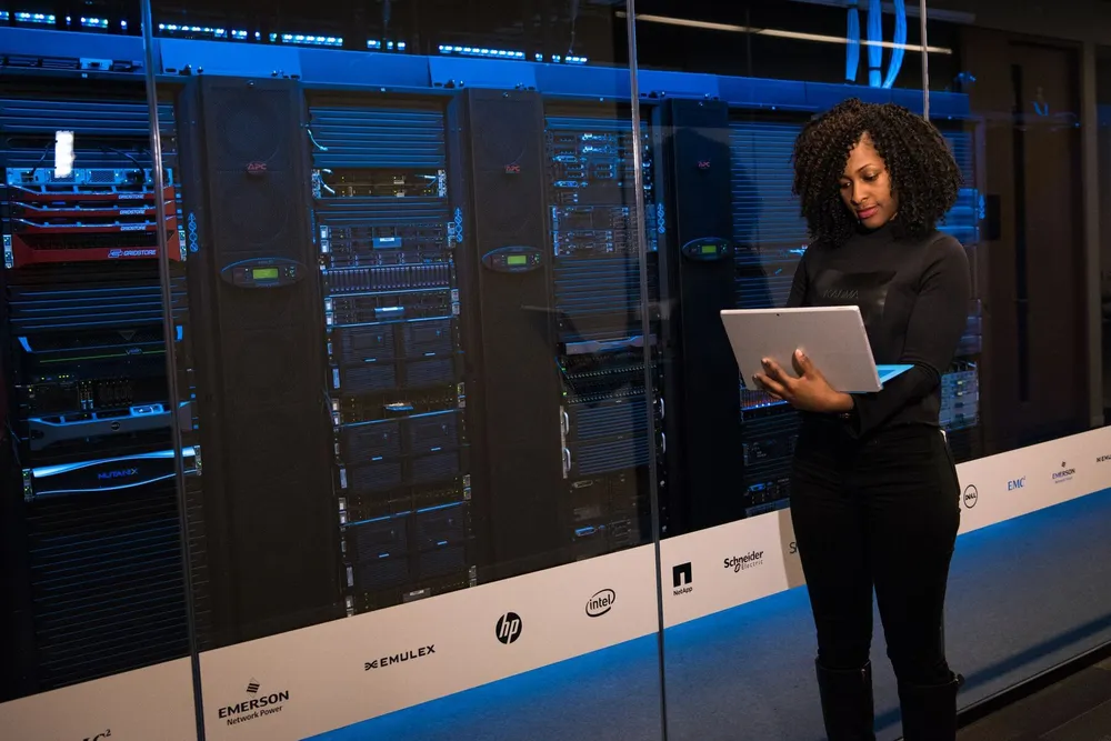 Engineer with a laptop beside server racks
