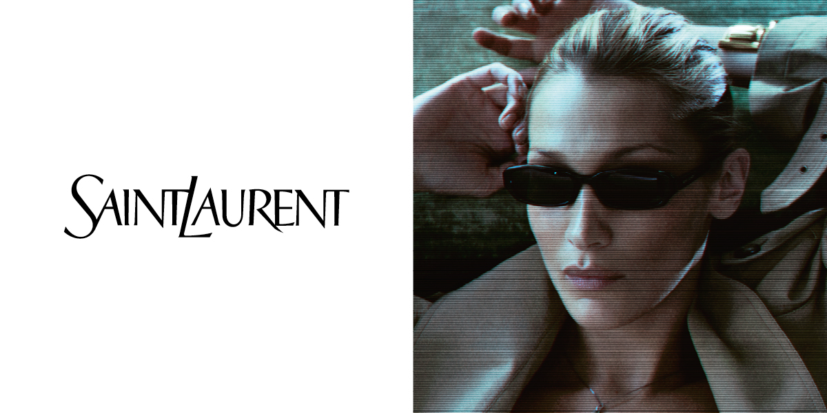 Osoba s tmavými slunečními brýlemi a béžovým trenčkotem s nápisem „Saint Laurent“. Součástí outfitu je top s krajkovým lemováním.