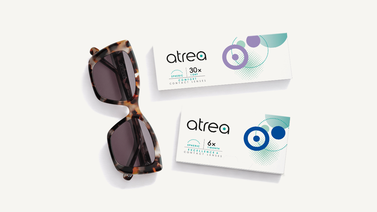 Sonnenbrille neben zwei Packungen Atrea Kontaktlinsen auf weißem Hintergrund.