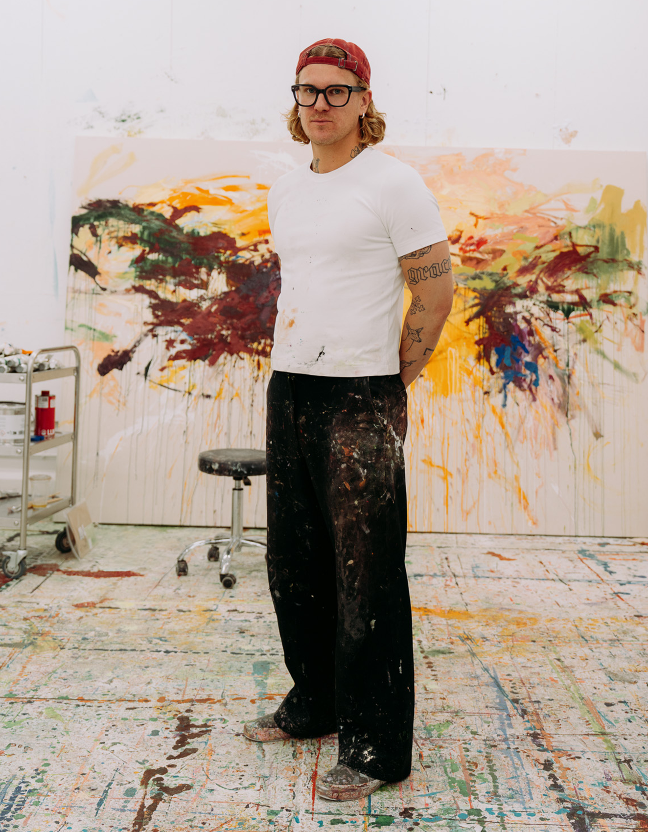 L’artiste Peter-Maximilian Ronsdorf dans son atelier devant une grande peinture colorée.