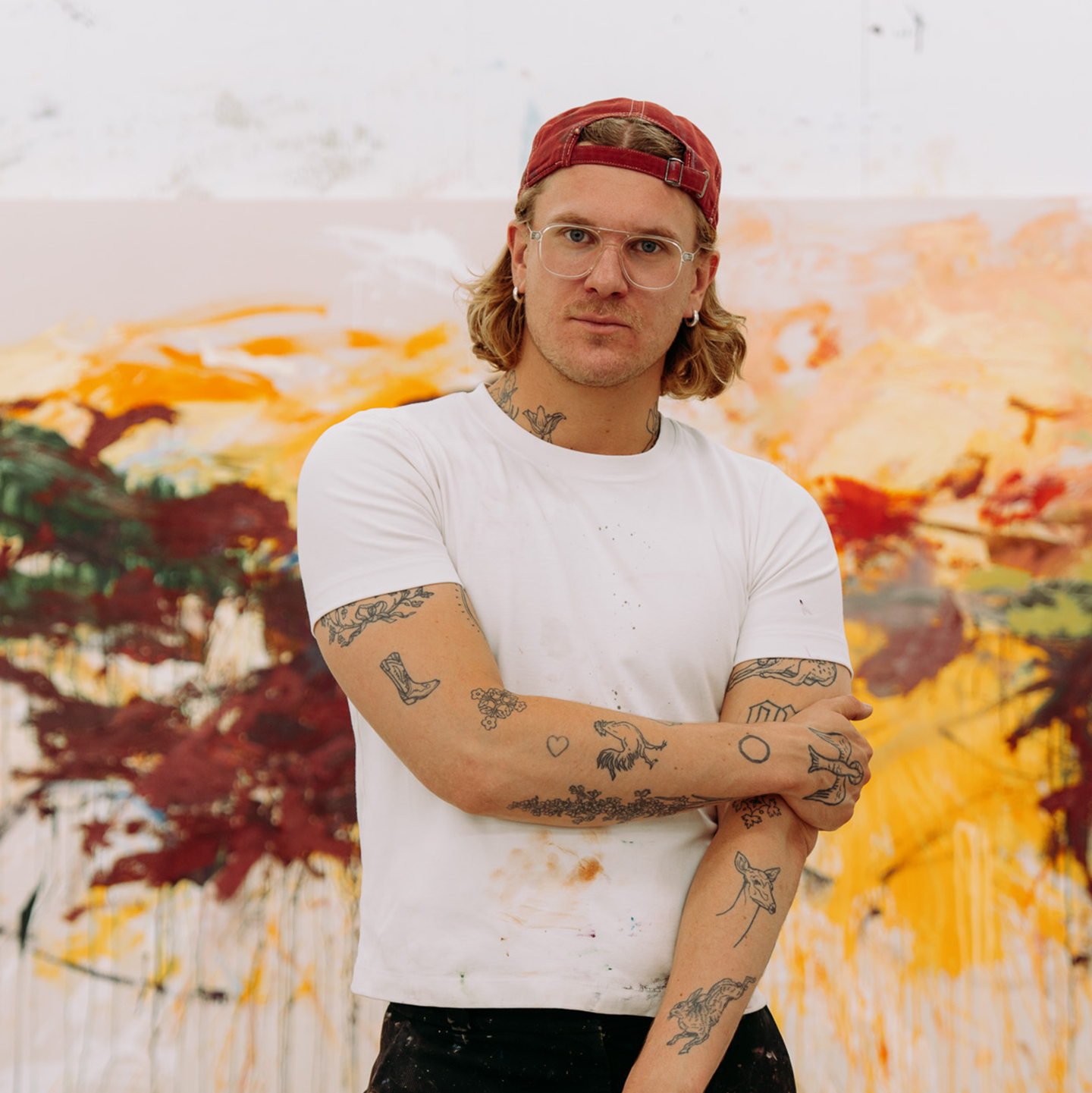 L’artiste Peter-Maximilian Ronsdorf dans son atelier devant une grande peinture colorée.