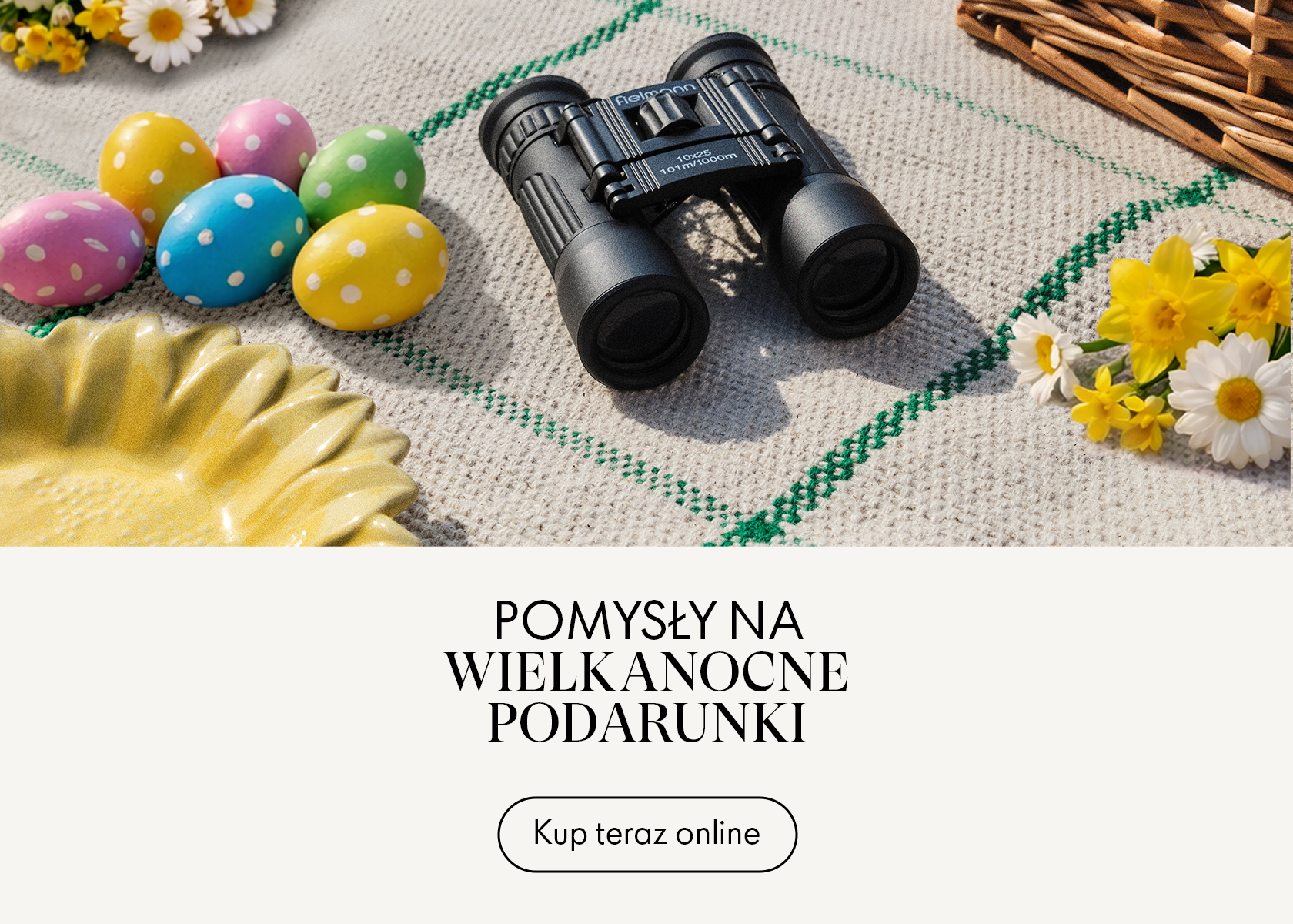 Lornetka na kocu piknikowym z kolorowymi pisankami, stokrotkami i koszykiem.