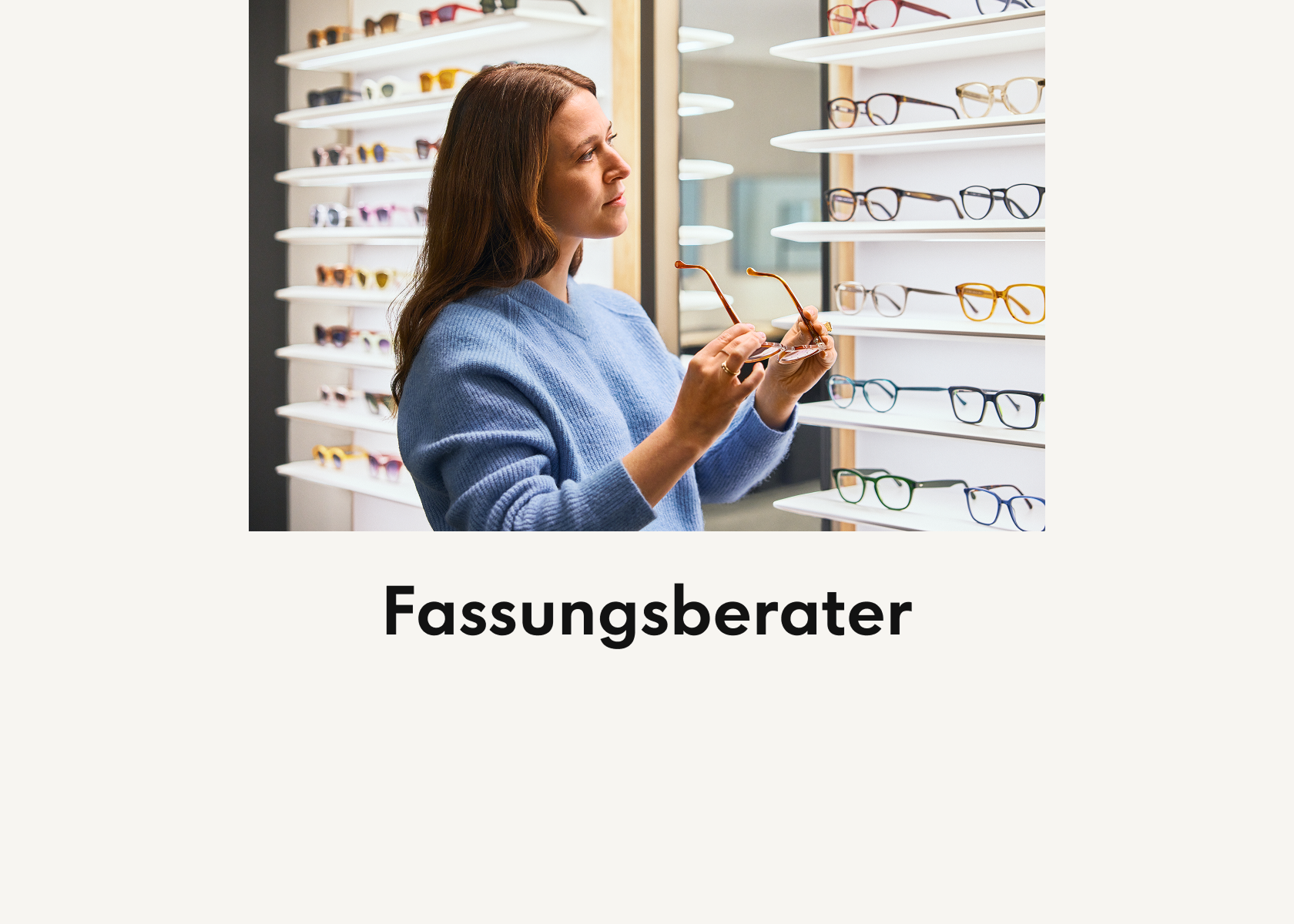Eine Frau in einem blauen Pullover begutachtet Brillengestelle in einem Geschäft, umgeben von Regalen mit verschiedenen Modellen. Der Text darunter lautet „Fassungsberater“.