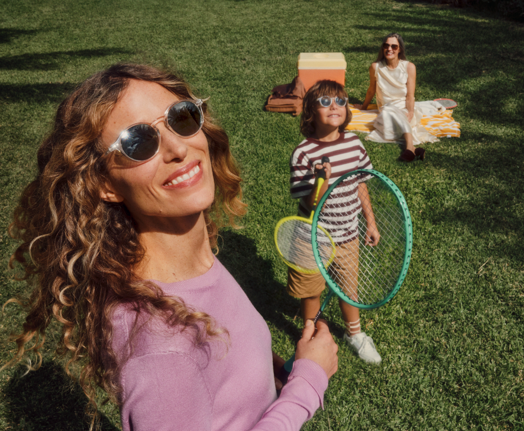 Eine Frau und zwei Kinder genießen Outdoor-Aktivitäten auf dem Rasen mit Schlägern.