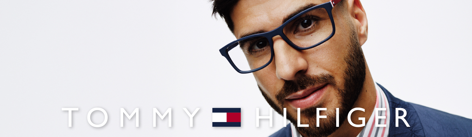 Ein Mann mit Brille und Bart trägt eine dunkelblaue Brille von Tommy Hilfiger
