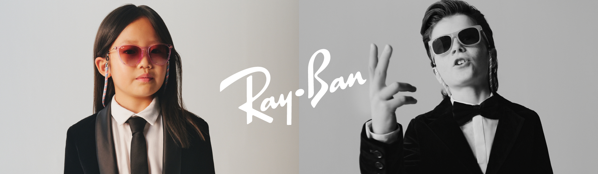 Dwoje dzieci w garniturach, noszących okulary przeciwsłoneczne z napisem „Ray-Ban”.