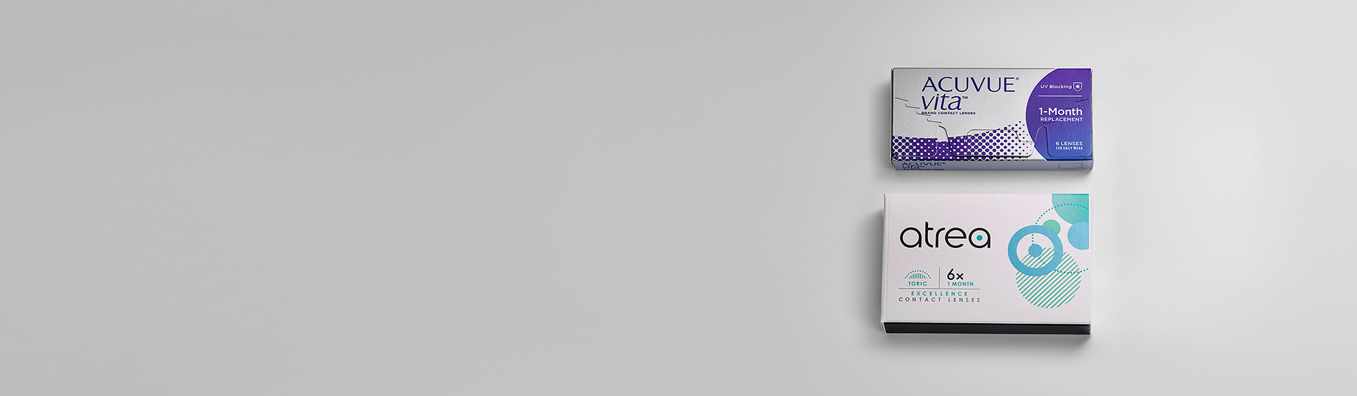 Grauer Hintergrund auf dem zwei Kontaktlinsenprodukte zu sehen sind.