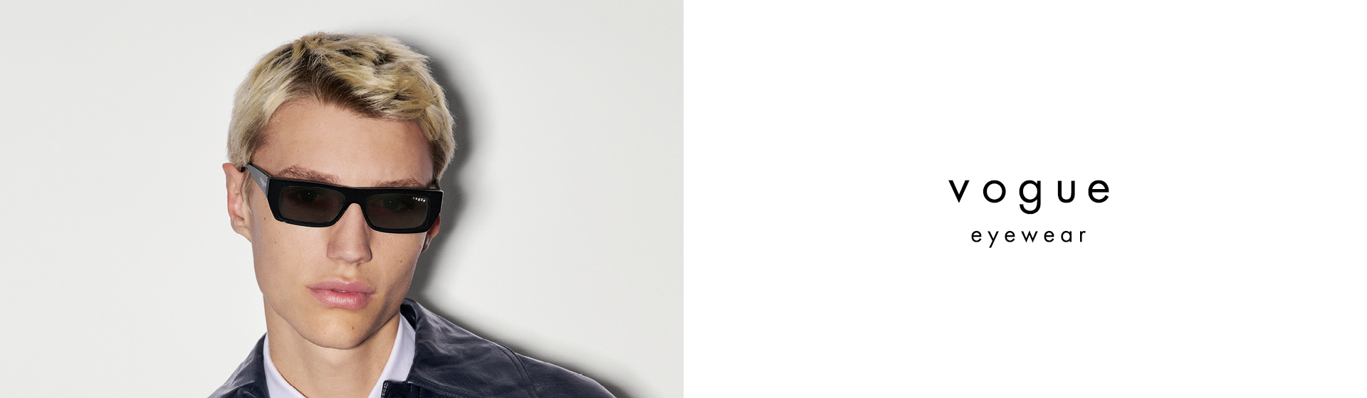 Person mit schwarzer Sonnenbrille und dunkler Jacke, mit kurzen blonden Haaren, neben dem „Vogue Eyewear”-Logo auf weißem Hintergrund.